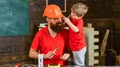 Father, parent with beard in helmet teaching son to use different tools in school workshop. Handyman concept. Boy, child