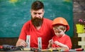 Father, parent with beard and little son in classroom, chalkboard on background. Father as handyman concept. Boy, child