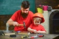 Father, parent with beard teaching little son to use hobnails and hammer. Workshop and handyman concept. Boy, child busy