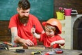 Father, parent with beard teaching little son to use tool screwdriver. Boy, child busy in protective helmet learning to Royalty Free Stock Photo