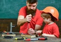 Father, parent with beard teaching little son to use tool screwdriver. Handyman and workshop concept. Boy, child busy in