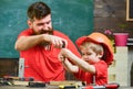 Father, parent with beard teaching little son to use tool screwdriver. Teamwork and assistance concept. Boy, child busy