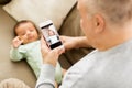 Father photographing baby by smartphone