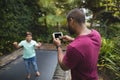 Father photographing son jumping on trampoline at park Royalty Free Stock Photo