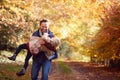 Father Playing Game Carrying Daughter On Family Walk Along Track In Autumn Countryside