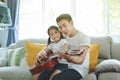 Father playing guitar with daughter with smile happily in home. Single dad love family concept Royalty Free Stock Photo