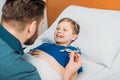 Father playing with sick little boy lying in hospital bed, dad and son in hospital Royalty Free Stock Photo