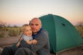 A father plays with his baby son at the tent in campground