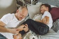 Father plays with his son 7-10 on bed. Dad tickles kids feet. Family, having fun