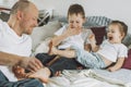 Father plays with two children on bed. Dad tickles kids feet. Family of daddy girl and boy Royalty Free Stock Photo