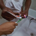 Father pour toothpaste on toothbrushes of children Royalty Free Stock Photo