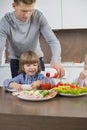 Father pouring juice for son at table in kitchen Royalty Free Stock Photo