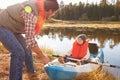 Father preparing launch for son in kayak on lakeside