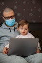 Man in protective mask with his daughter and laptop