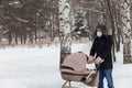 Father pushing baby stroller and walking at park in blizzard