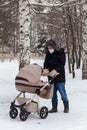 Father pushing baby stroller and walking at park in blizzard. Russia