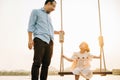 father pushing his cute daughter on a swing and both of them smiling Royalty Free Stock Photo