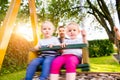 Father pushing his daughters on swing in a park. Royalty Free Stock Photo