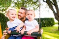 Father pushing his daughters on swing in a park. Royalty Free Stock Photo