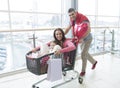 Father pushing mother and young daughter in shopping trolley