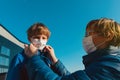 Father puts a medical mask on son outdoors