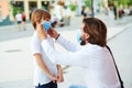 Father puts a protective mask on his son. Medical mask to prevent coronavirus. Dad and kid walking city