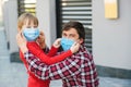 Father puts on son face mask outdoors. Coronavirus epidemic, virus symptoms. Family wearing face mask for protection during the