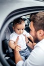 Father putting child in car seat, going for a family roadtrip