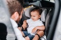 Father putting one year old baby in child car seat and smiling. Lifestyle concept Royalty Free Stock Photo