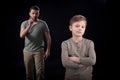 Father quarreling at indifferent son standing with crossed arms