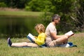 Father read a book with son in a park outdoors. Father and child son reading outdoor on green nature background. Dad Royalty Free Stock Photo