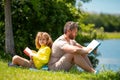 Father read a book with son in a park outdoors. Father and child son reading outdoor on green nature background. Dad Royalty Free Stock Photo