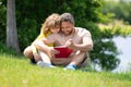 Father read a book with son in a park outdoors. Father and child son reading outdoor on green nature background. Dad Royalty Free Stock Photo