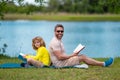 Father read a book with son in a park outdoors. Father and child son reading outdoor on green nature background. Dad Royalty Free Stock Photo