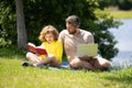 Father reading book with son in park, preparing school homework together, parenting. Summer lifestyle. Parenting and Royalty Free Stock Photo