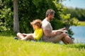 Father reading book with son in park, preparing school homework together, parenting. Summer lifestyle. Parenting and Royalty Free Stock Photo