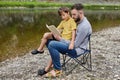 Father is reading a book to his son in nature