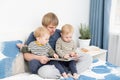 father reading a book to his sons twins on bed at home, spending time together Royalty Free Stock Photo