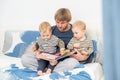 father reading a book to his sons twins on bed at home, spending time together Royalty Free Stock Photo