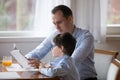 Father reading book to son aloud at kitchen at home