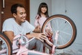 A father repairing spokes of a bicycle wheel with daughter Royalty Free Stock Photo