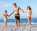 Father Running With Children Along Sandy Beach