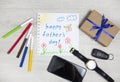 Father`s day. Children`s drawing and gift next to men`s accessories. Composition happy father`s day