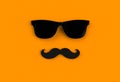 Father`s day concept. Hipster black sunglasses and funny moustache on orange background.