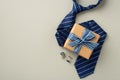 Father`s Day concept. Top view photo of craft paper gift box with striped ribbon bow blue tie and cufflinks on isolated pastel Royalty Free Stock Photo