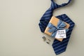 Father`s Day concept. Top view photo of craft paper gift box with striped ribbon bow and postcard blue necktie and cufflinks on Royalty Free Stock Photo