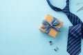 Father`s Day concept. Top view photo of craft paper giftbox with ribbon bow tie clip cufflinks and blue necktie on isolated paste