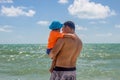 Father`s day. dad holds a toddler in his arms and shows the child the sea Royalty Free Stock Photo