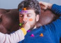 Father`s day. Young man sleeping while his little daughter paints his face Royalty Free Stock Photo