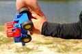 Father's large hand pass plastic toy truck to hand of a little boy. Hands in blue and black shirts.